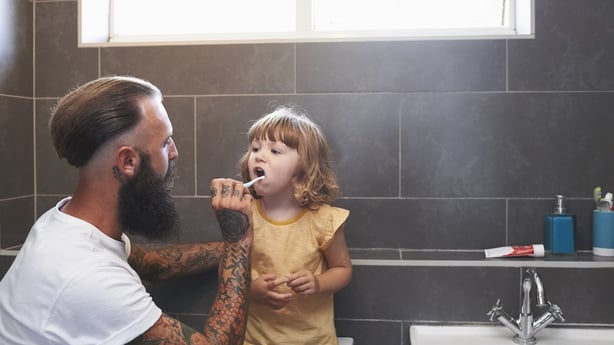 dad brushing daughter's teeth